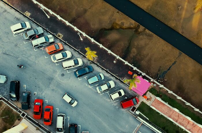 Aerial view of a parking lot near a riverbank, evoking a sense of unresolved mysteries people carry with them.