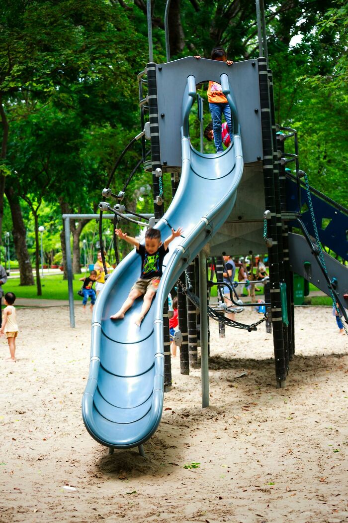 Children playing on a slide at a park playground, illustrating modern parenting trends in outdoor activities.