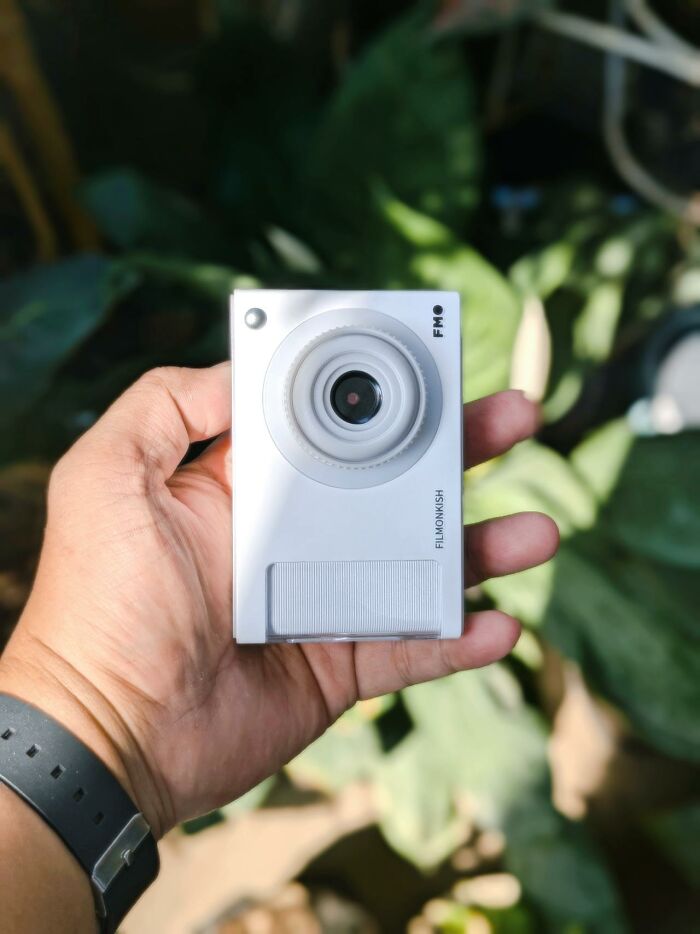 Hand holding a small white camera, one of the unusual personal belongings found at a lost and found location.