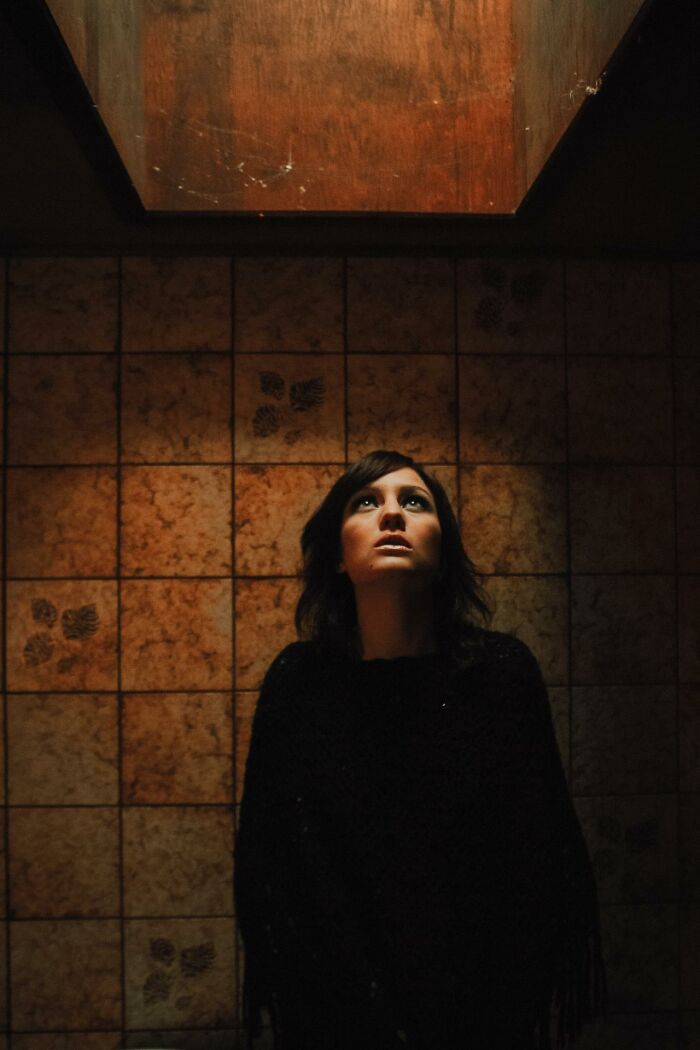 Woman looking up in dim room with tile walls, illustrating disturbing facts people learned against their will.