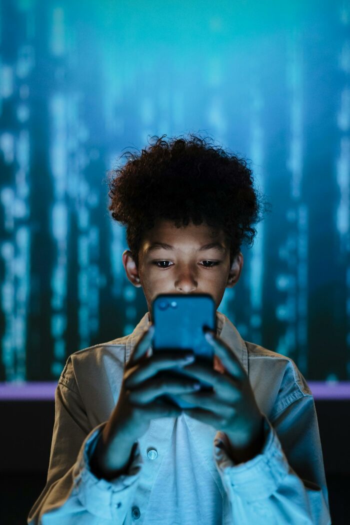 Young boy focused on smartphone screen, illustrating modern parenting trends in digital technology use.