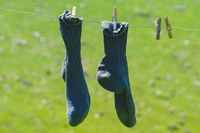 Pair of dark socks hanging on a clothesline, symbolizing unresolved mysteries people carry with them outdoors.