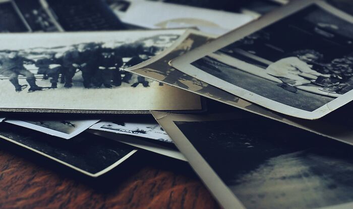 A pile of iconic vintage photos spread on a wooden surface for true historians to match with historic events.