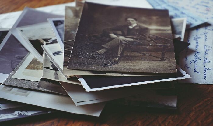 Stack of old black and white photos and letters representing unresolved mysteries people carry with them over time.