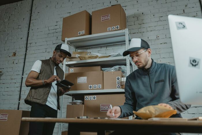 Two men working with packaging boxes in a warehouse, highlighting small design mistakes causing workspace inefficiencies.