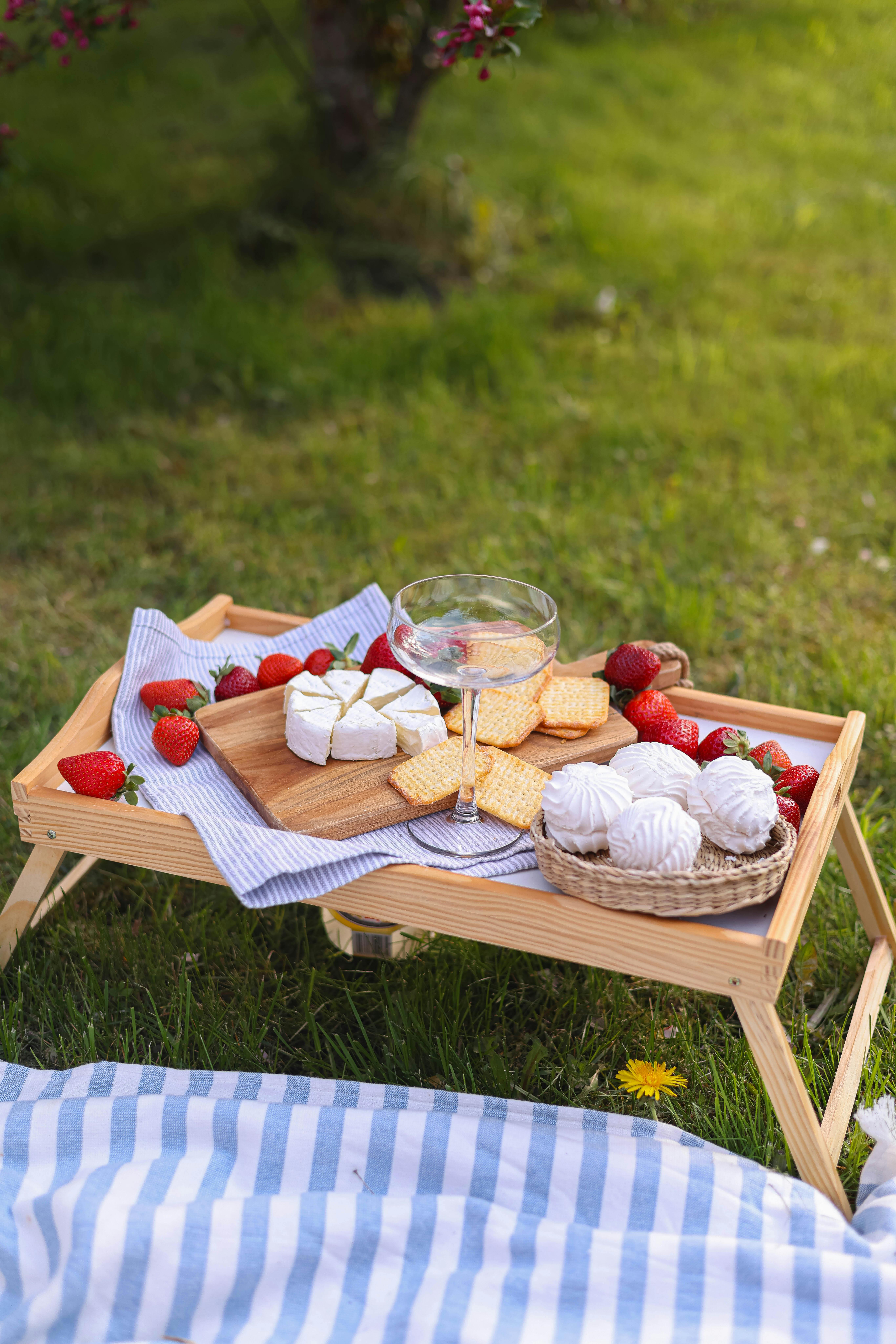 Breakfast tray with cheese, crackers, strawberries, and meringues set outdoors for morning love messages picnic. Breakfast tray with cheese, crackers, strawberries, and meringues set outdoors for morning love messages picnic.