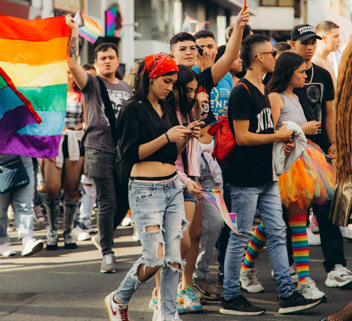 Teen at a pride march holding a rainbow flag, showcasing courage and respect in a gay teen's powerful message. Teen at a pride march holding a rainbow flag, showcasing courage and respect in a gay teen's powerful message.