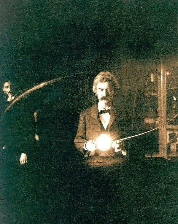 Historical picture of a man holding an early light bulb, showcasing a classic iconic moment in electrical invention history.