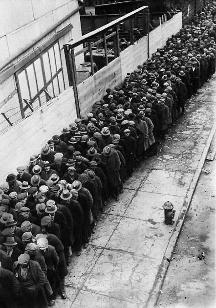 Long queue of men in coats and hats waiting outside during the Great Depression, a classic historical picture.