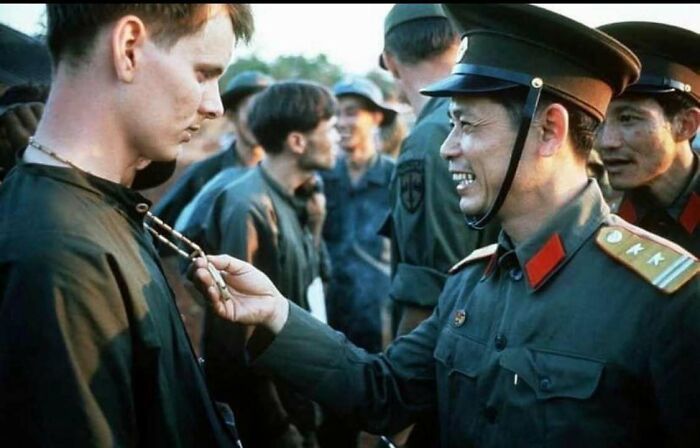 A classic and iconic historical picture showing a smiling officer interacting with a young man in uniform.