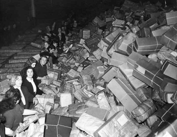 Group of women sorting large piles of wrapped packages in a classic and iconic historical black and white photograph.