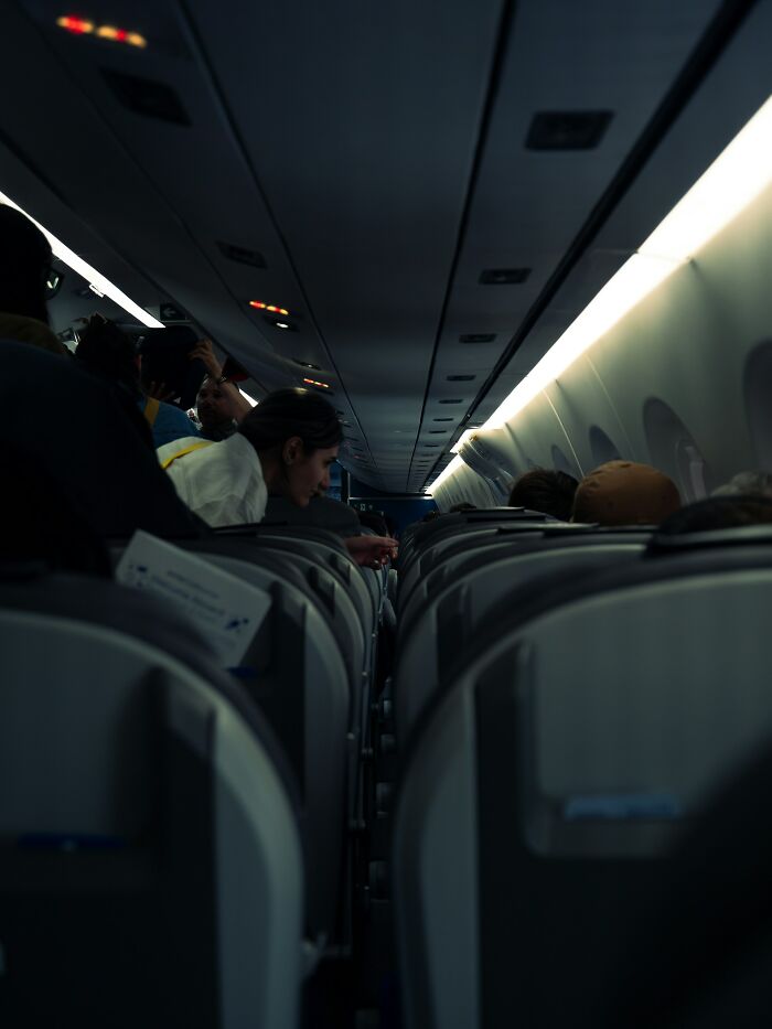 Passengers seated inside a dimly lit airplane cabin, illustrating an example of instant karma in everyday travel.