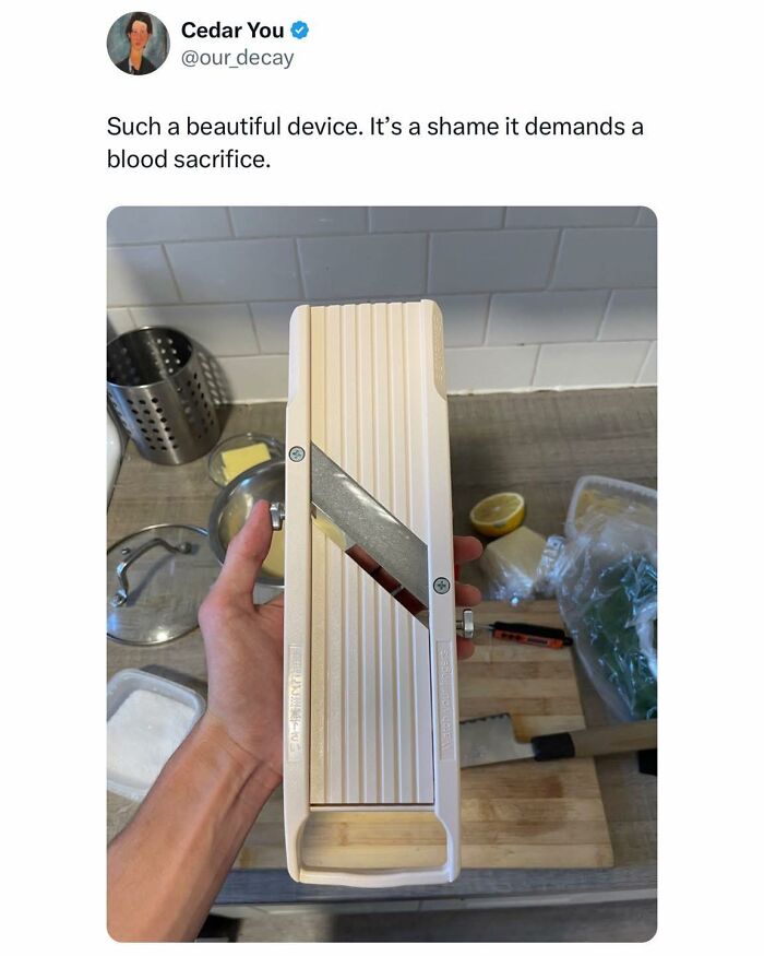 Hand holding a mandoline slicer with a sharp blade, illustrating the humor in food memes about kitchen tools.