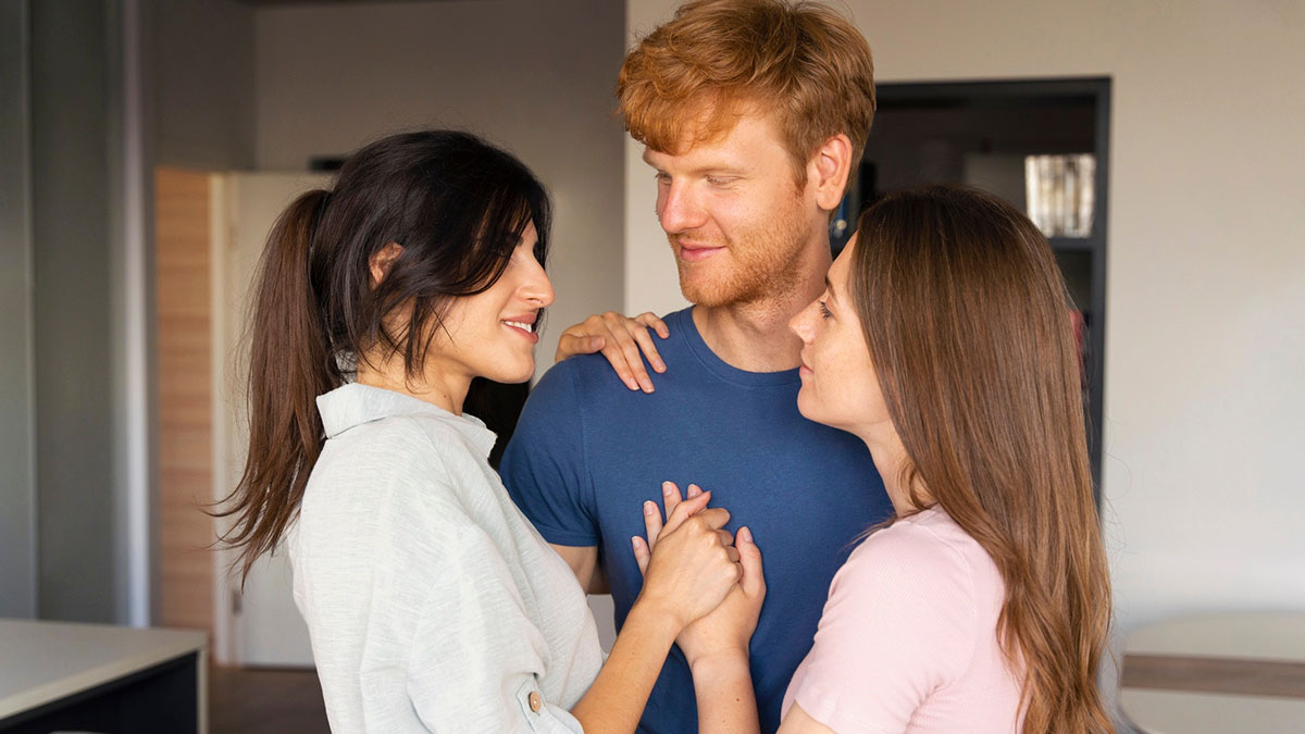 A polyamorous couple showing affection while a man stands between two women, illustrating parents favoring partners over kid.