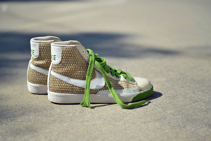 Pair of worn sneakers with green laces on concrete, illustrating simple lifestyle choices to easily save thousands.
