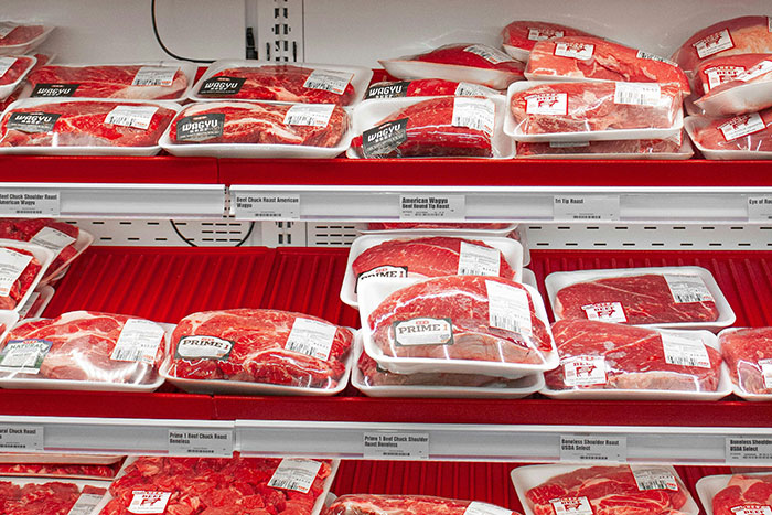 Packages of beef cuts displayed on refrigerated shelves illustrating poor person hacks to easily save thousands on groceries.