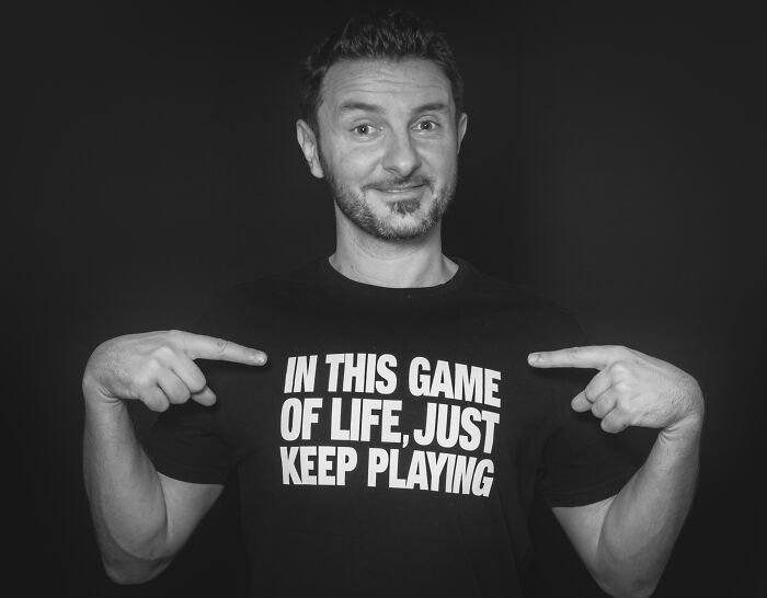 Man pointing at motivational message on black shirt, illustrating signs someone is stuck in their high school era years later.
