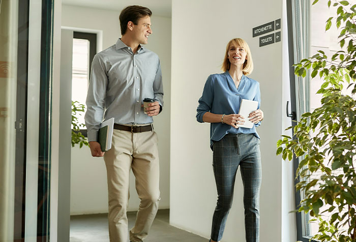 Man and woman walking and smiling in office hallway, representing microfeminism and clapping back at toxic masculinity.