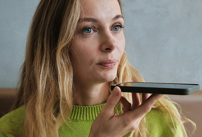 Young woman holding a smartphone, speaking with determination, reflecting acts of microfeminism against toxic masculinity.