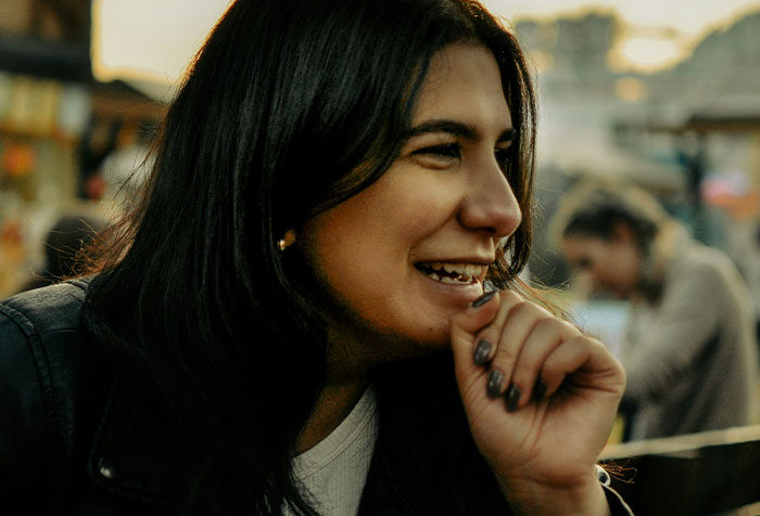 Young woman smiling confidently outdoors, embodying strength and microfeminism against toxic masculinity.