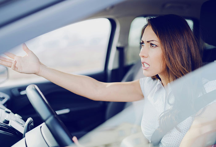 Woman in car expressing frustration with a gesture, illustrating acts of microfeminism against toxic masculinity.