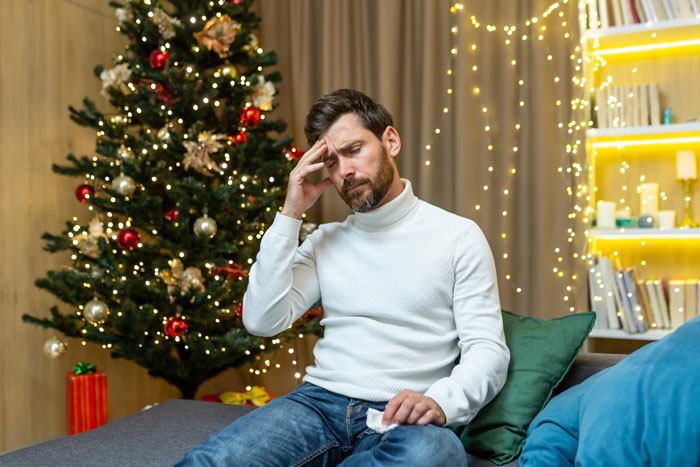 28-year-old man frustrated and holding tissue near Christmas tree, reacting to unexpected pregnancy news from girlfriend. 28-year-old man frustrated and holding tissue near Christmas tree, reacting to unexpected pregnancy news from girlfriend.