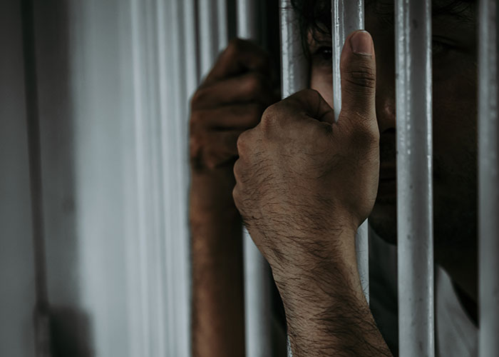 Close-up of an inmate gripping prison bars, illustrating surprising facts and misconceptions about prison life.