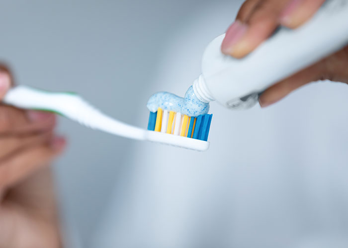 Person applying toothpaste on a toothbrush, illustrating surprising facts and misconceptions about prison life hygiene.