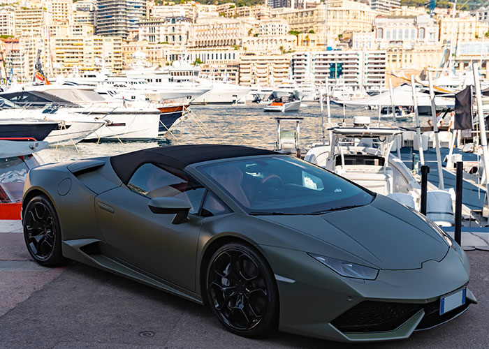 Matte black luxury sports car parked near yachts at a marina, illustrating surprising facts and misconceptions about prison life.