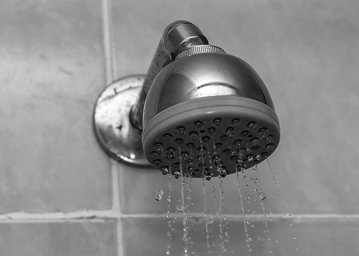 Close-up of a showerhead with running water, representing daily life and surprising facts about prison life.