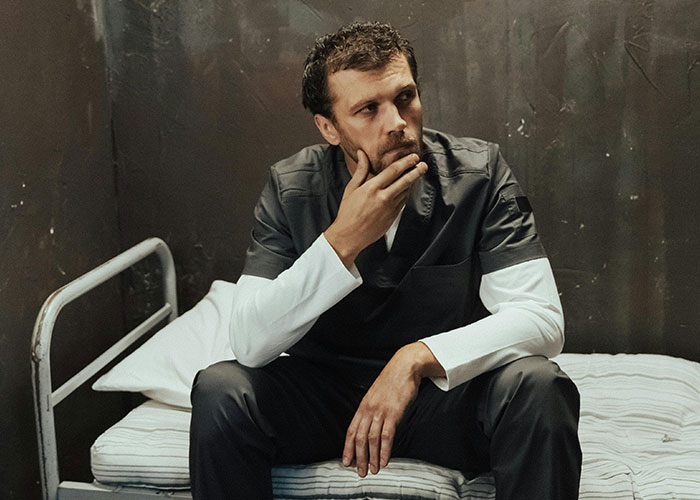 Inmate sitting on a prison bed looking thoughtful, illustrating surprising facts and misconceptions about prison life.