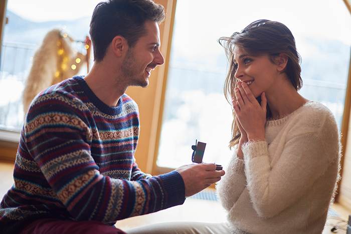 Man proposing to woman indoors with a ring, highlighting a bride’s emotional moment before wedding vows. Man proposing to woman indoors with a ring, highlighting a bride’s emotional moment before wedding vows.