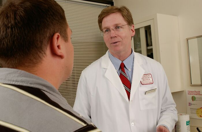 Doctor in white coat consulting with a male patient about common habits that might wreck long-term health.