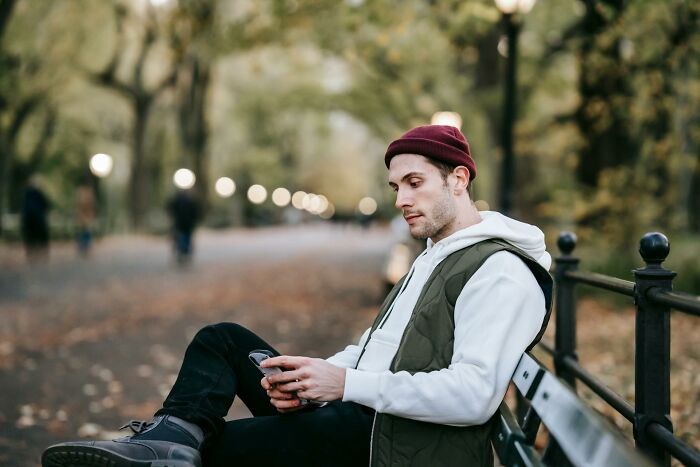 Young man sitting on park bench using phone, reflecting on stories of quitting jobs in record time.