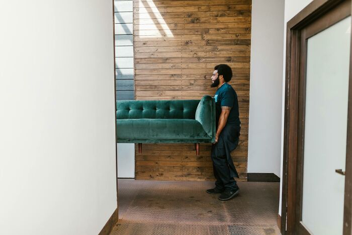 Man carrying a green sofa through a hallway, illustrating stories from folks who quit their jobs in record time.