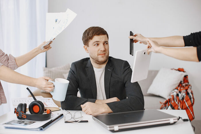 Man overwhelmed at desk with laptop and papers, illustrating wild stories of folks who quit their jobs quickly.