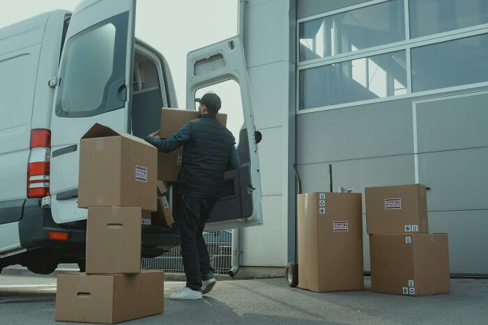 Person loading moving boxes into a van outside a warehouse, illustrating stories of quitting jobs in record time.