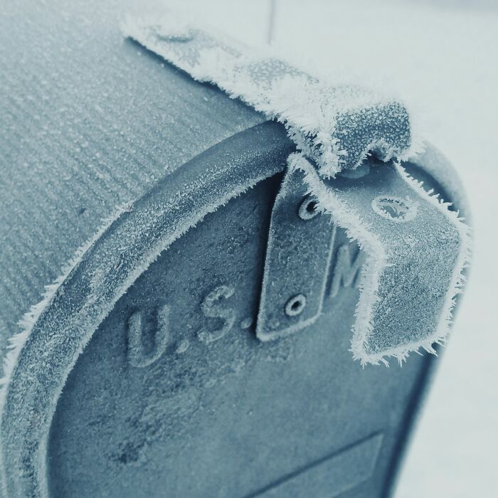 Frost-covered U.S. mailbox highlighting harsh winter realities of being a postal worker outdoors.