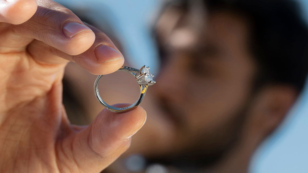 Close-up of a hand holding a family heirloom ring, highlighting the intricate design and gemstone details.
