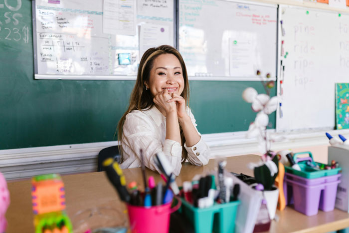 Young woman at desk looking thoughtful in classroom setting, illustrating colleague with inappropriate intentions scenario. Young woman at desk looking thoughtful in classroom setting, illustrating colleague with inappropriate intentions scenario.
