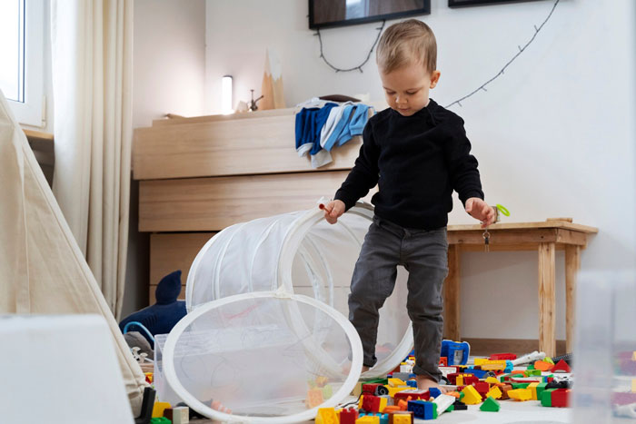 Toddler plays recklessly with toys scattered on the floor while teenager refuses to babysit due to his behavior. Toddler plays recklessly with toys scattered on the floor while teenager refuses to babysit due to his behavior.