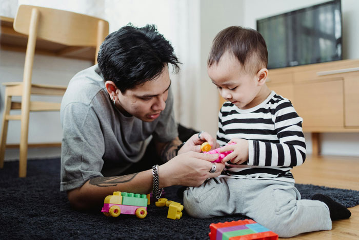 Teen caring for a young child playing with colorful toys on the floor in a bright home setting. Teen caring for a young child playing with colorful toys on the floor in a bright home setting.