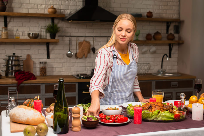 Young woman arranging Christmas menu dishes at table, illustrating picky eater demands and family meal adjustments. Young woman arranging Christmas menu dishes at table, illustrating picky eater demands and family meal adjustments.