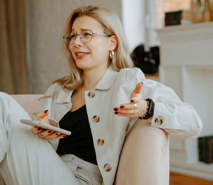 Woman with glasses and beige outfit holding phone, discussing picky eater demanding family change entire Christmas menu. Woman with glasses and beige outfit holding phone, discussing picky eater demanding family change entire Christmas menu.