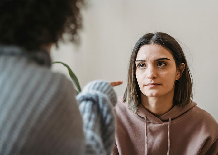 Two women having a serious conversation indoors, illustrating discomfort related to bride and groom and hairy armpits conflict. Two women having a serious conversation indoors, illustrating discomfort related to bride and groom and hairy armpits conflict.