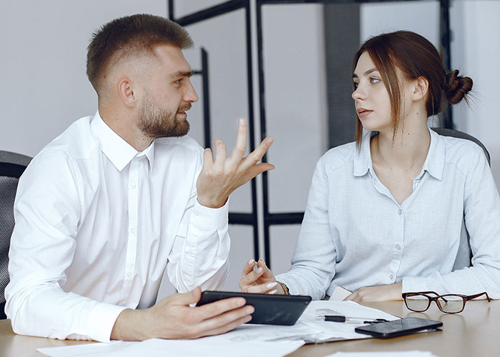 Man and woman in office having tense discussion about shady fund manager refusing to show receipts during meeting Man and woman in office having tense discussion about shady fund manager refusing to show receipts during meeting