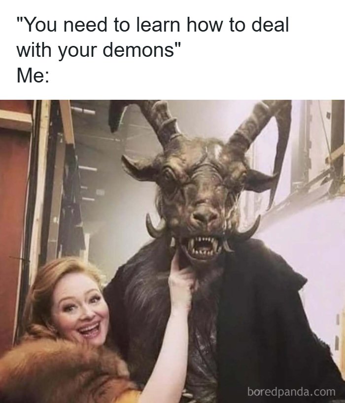 Woman smiling and touching a person in a detailed demon costume, illustrating memes to handle reality with humor.