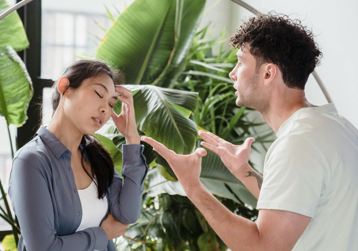 Young man arguing with woman indoors, illustrating HOA snitch conflict over grass height with tape measure and rulebooks nearby. Young man arguing with woman indoors, illustrating HOA snitch conflict over grass height with tape measure and rulebooks nearby.