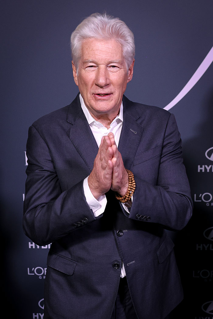 Richard Gere in a dark suit with hands together, attending a formal event related to Oscars news. Richard Gere in a dark suit with hands together, attending a formal event related to Oscars news.