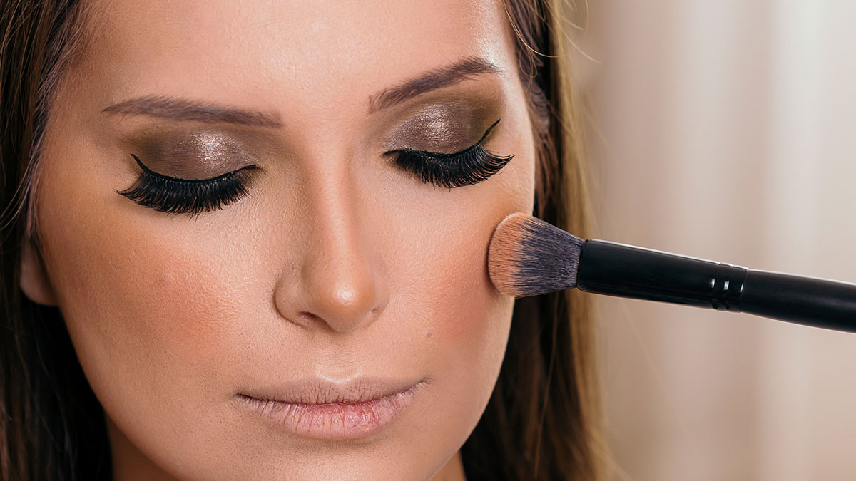 Close-up of a woman with makeup being applied, highlighting women online roasting men about no makeup look preferences.